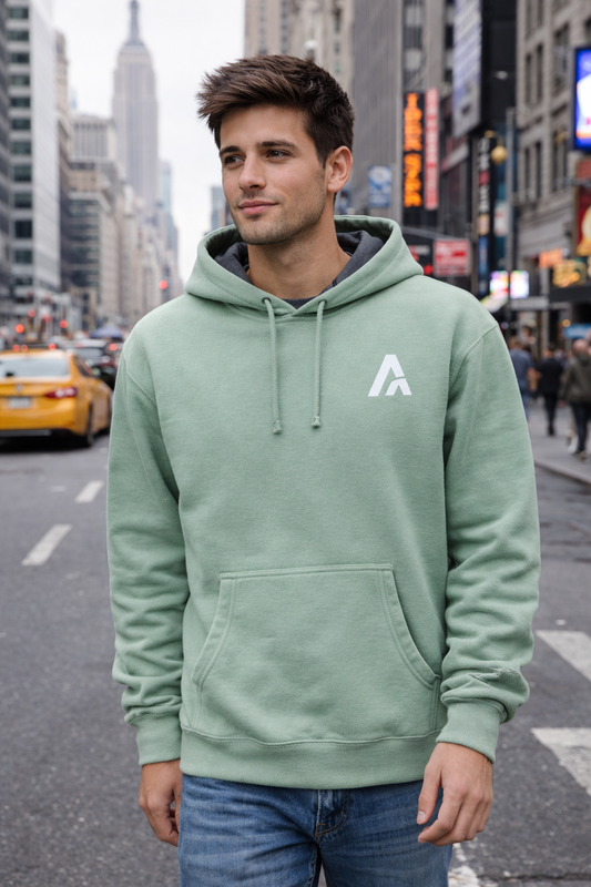 Male model wearing a mint green hoodie with grey hood lining and embroidered Atlas A monogram on a city street.
