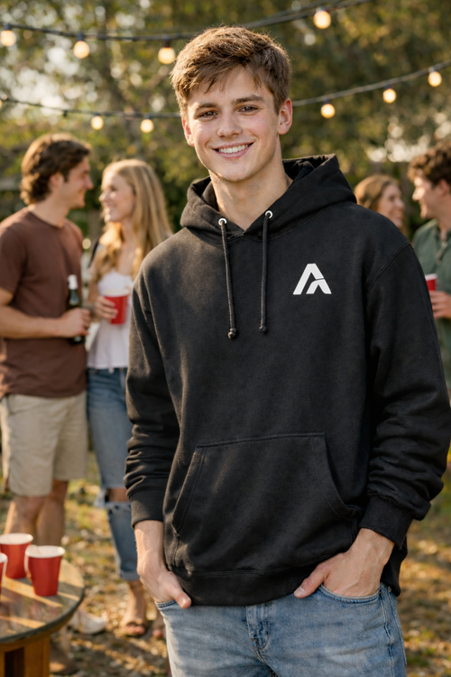 Person wearing a black hoodie with a logo at an outdoor event