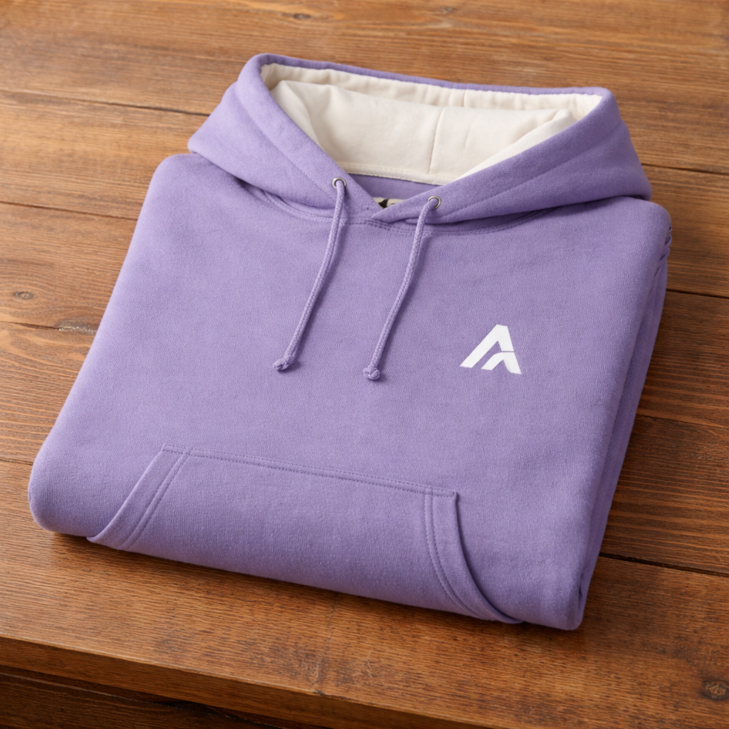 Folded purple hoodie with a white logo on a wooden surface