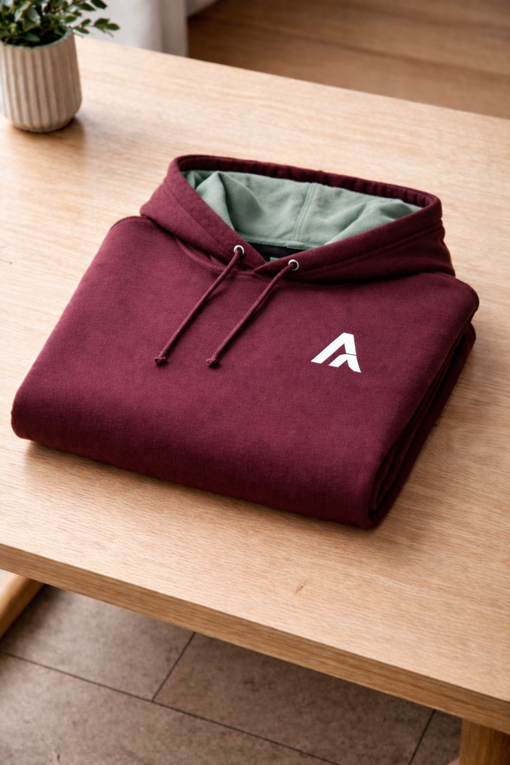 Maroon hoodie with a white letter 'A' on a wooden table