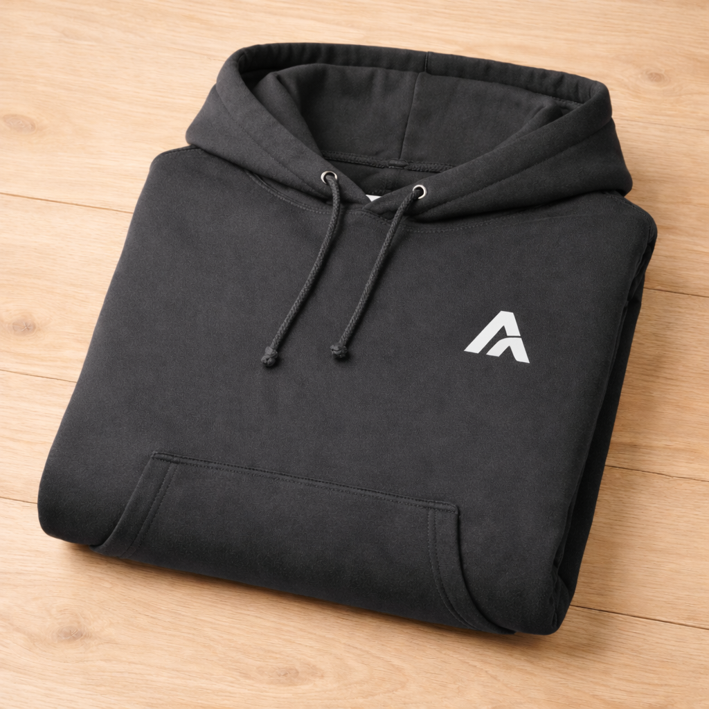 Folded black hoodie with a white logo on a wooden surface