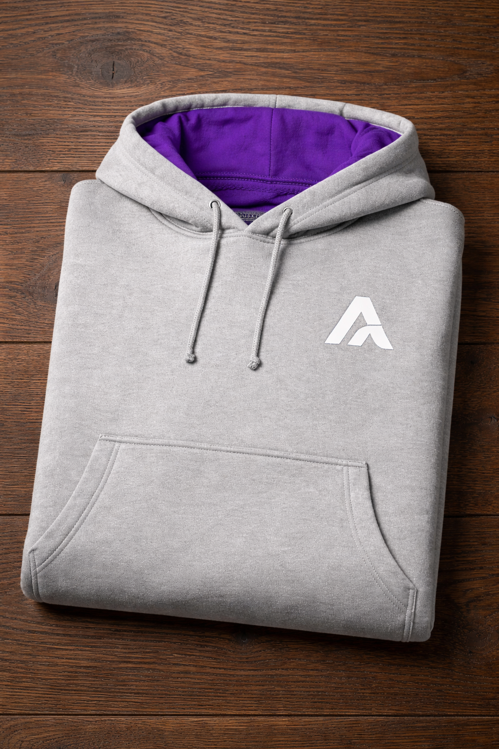Folded gray hoodie with a white logo on a wooden surface