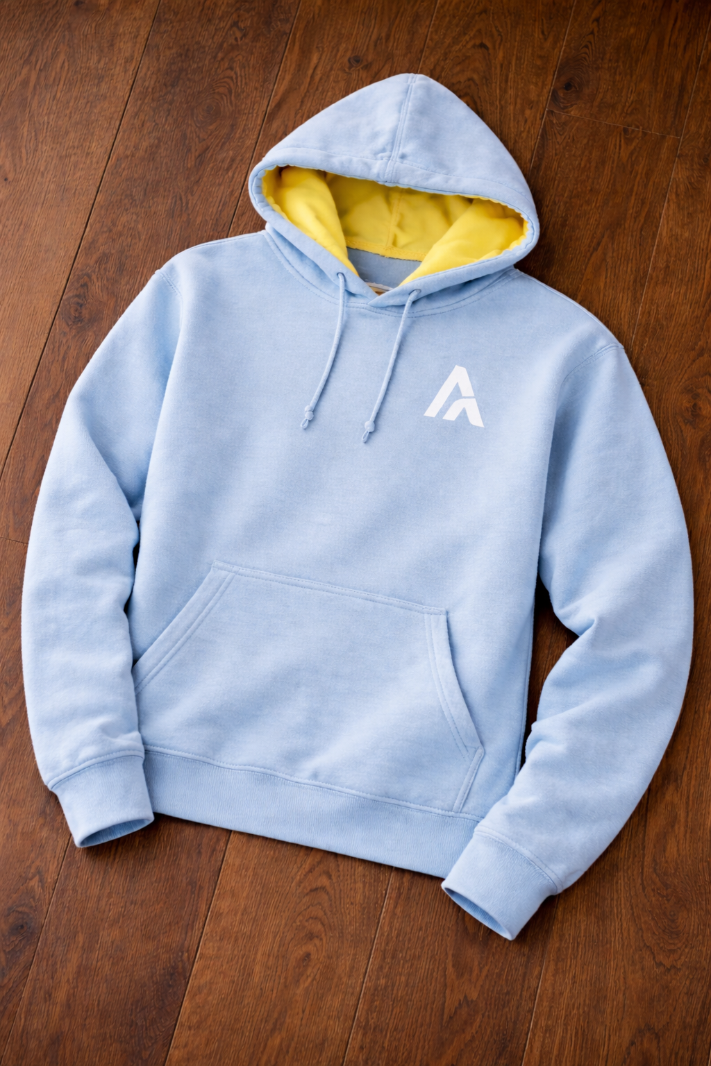 Light blue hoodie with a logo on a wooden surface