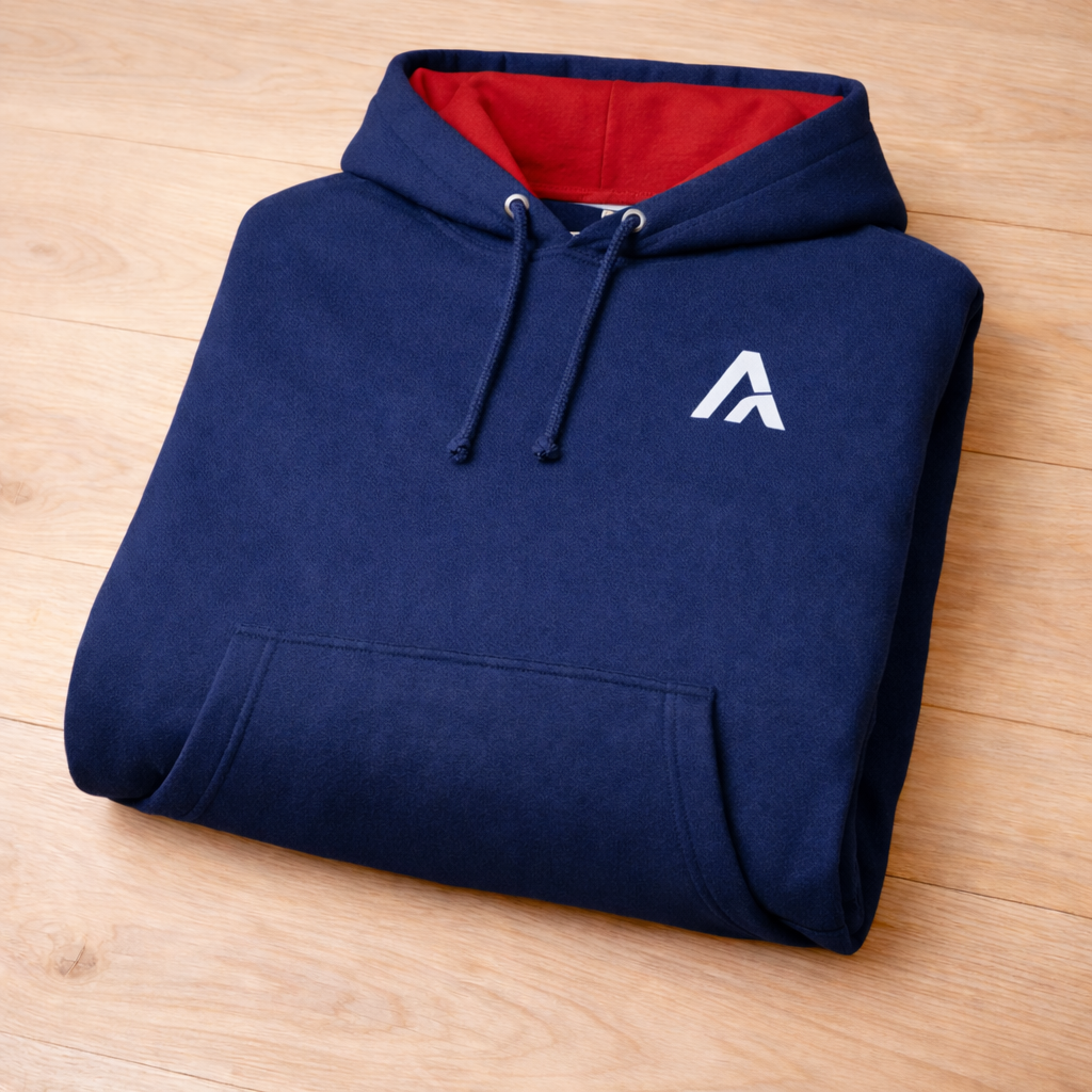 Folded navy blue hoodie with a white logo on a wooden surface