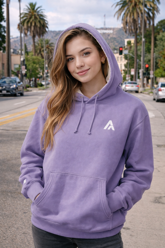 Model wearing a purple hoodie with white hood lining and embroidered Atlas A monogram, hood up on an urban street.

