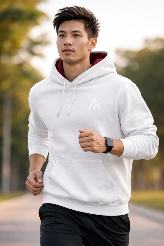 Male model wearing an Atlaswear white premium hoodie with burgundy hood lining and embroidered logo, running outdoors in a casual active streetwear setting