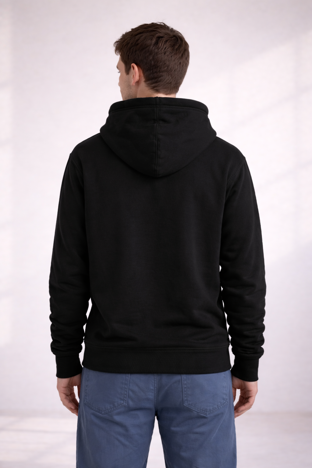 Back view of a man wearing a black pullover hoodie with hood down and ribbed hem.