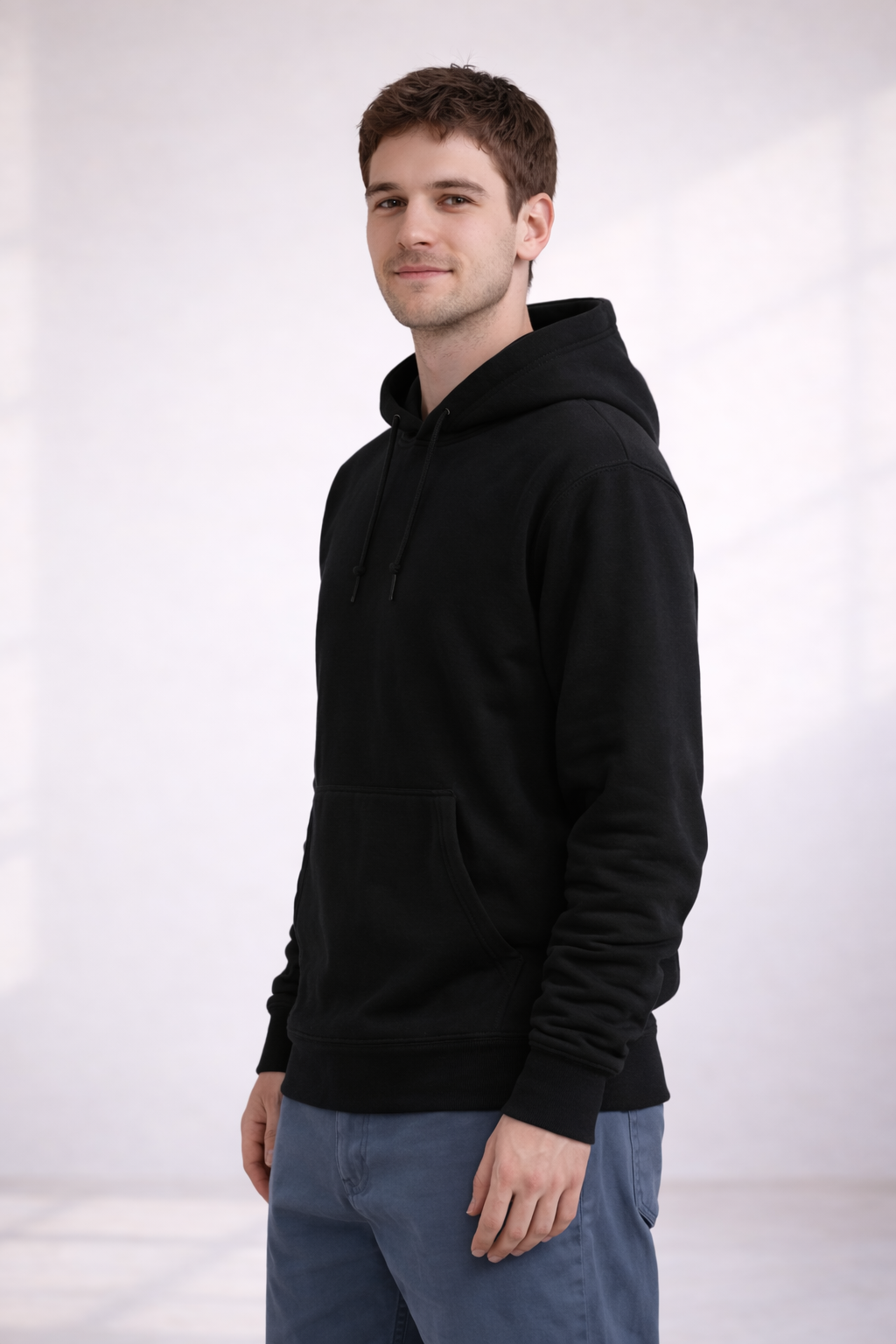 Man wearing a black pullover hoodie shown in a front angled view with kangaroo pocket and drawstring hood.