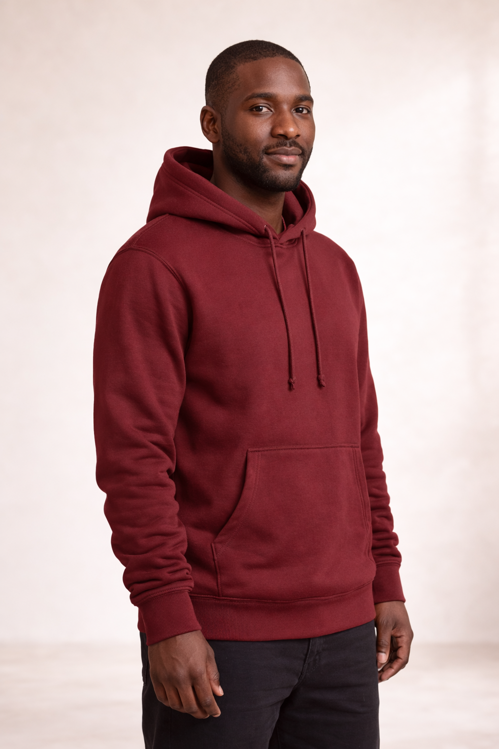 Man wearing a brick red pullover hoodie shown in angled front view with drawstring hood and kangaroo pocket.
