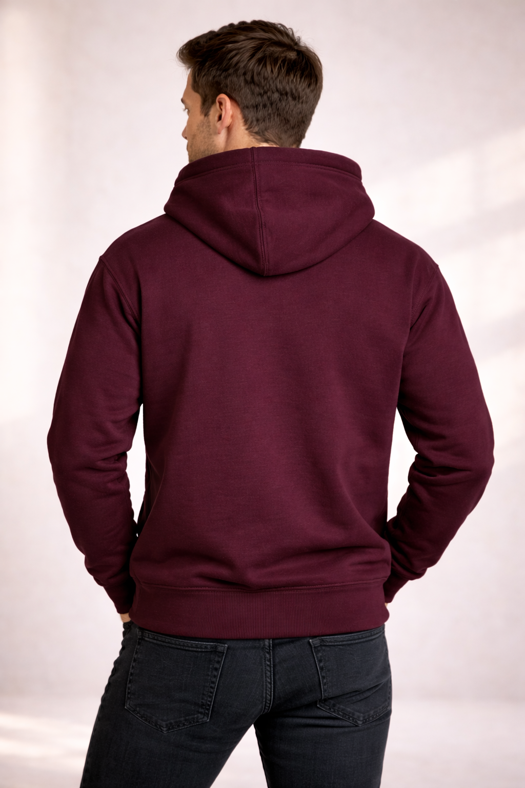 Back view of a man wearing a burgundy pullover hoodie with hood and ribbed hem.