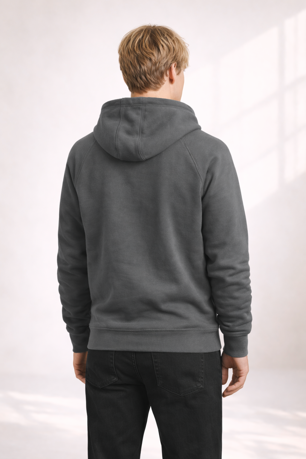 Back view of a man wearing a mens charcoal gray pullover hoodie with hood and ribbed hem.
