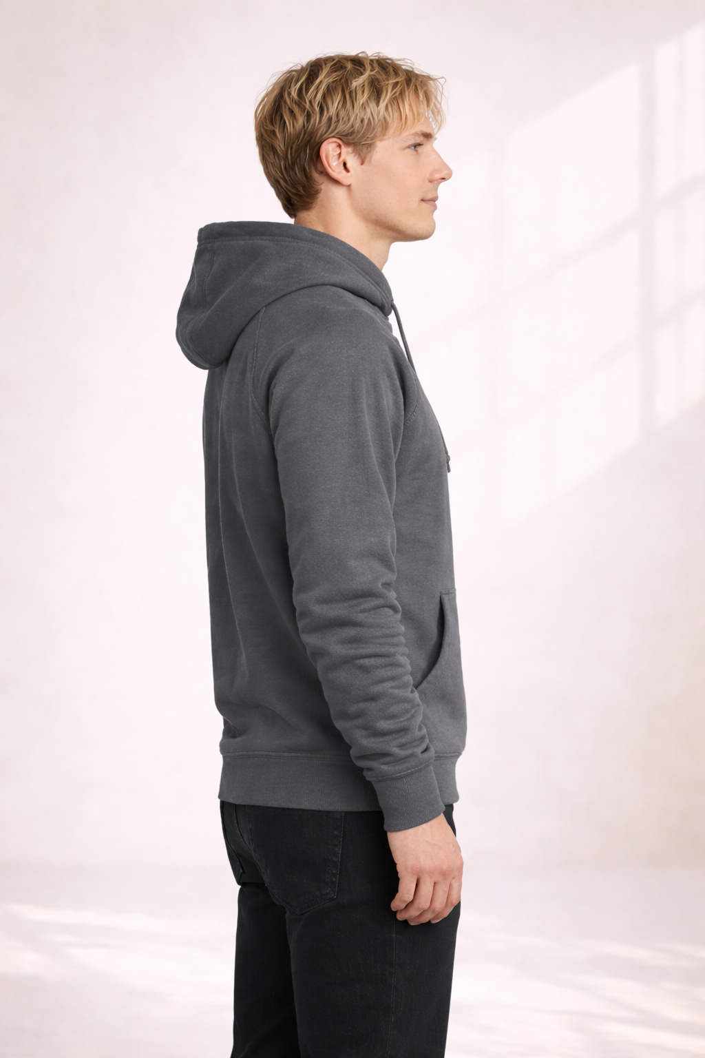 Side profile of a man wearing a mens charcoal gray pullover hoodie showing relaxed fit and hood.