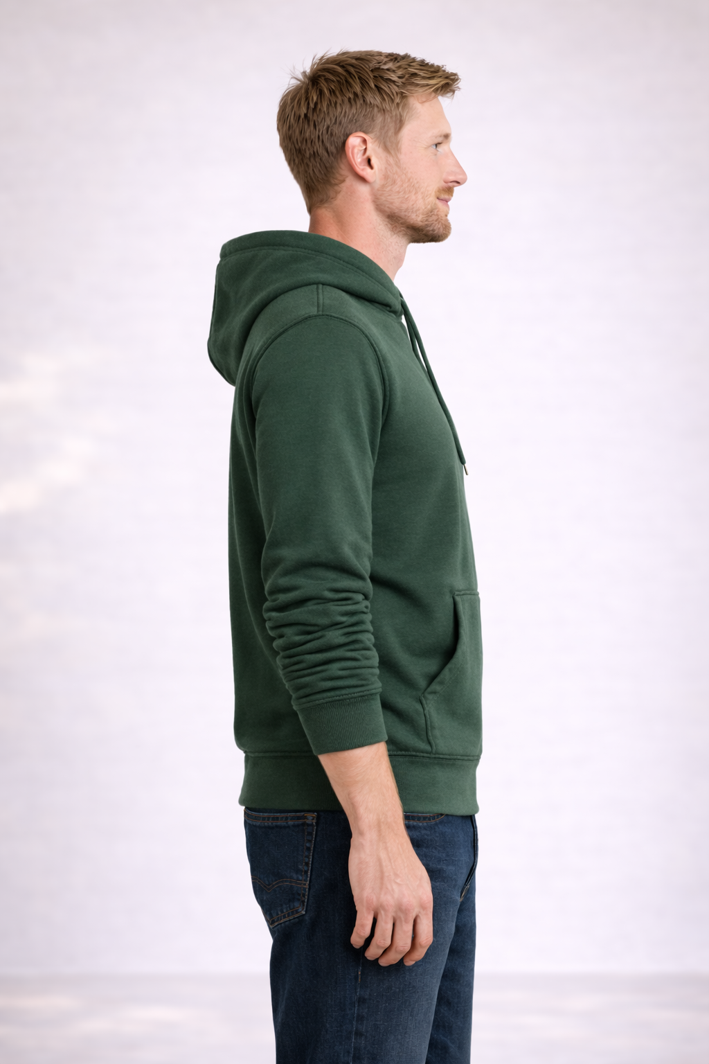 Side profile of a man wearing a mens forest green pullover hoodie showing relaxed fit and hood.