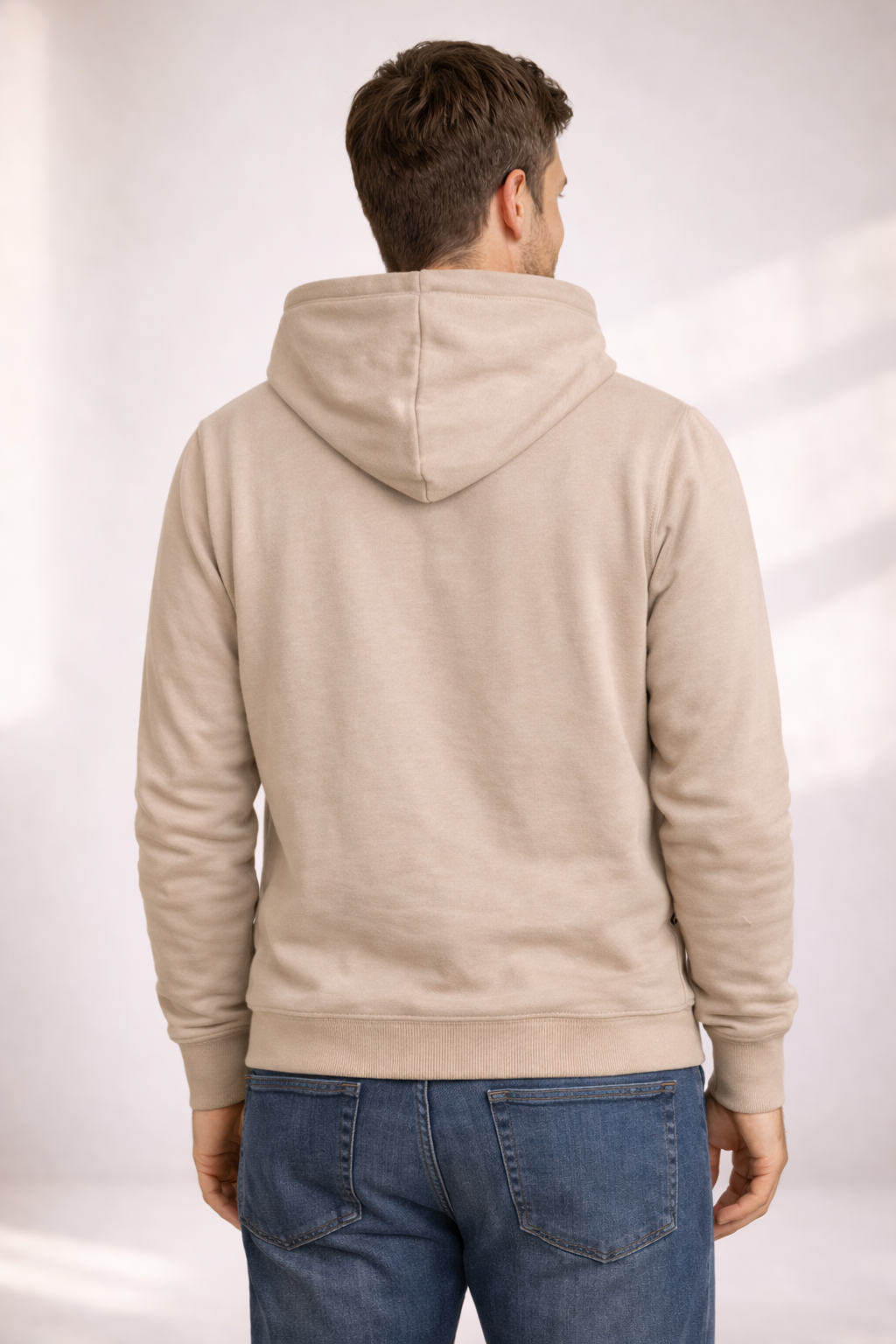 Back view of a man wearing a light beige pullover hoodie with hood and ribbed hem.