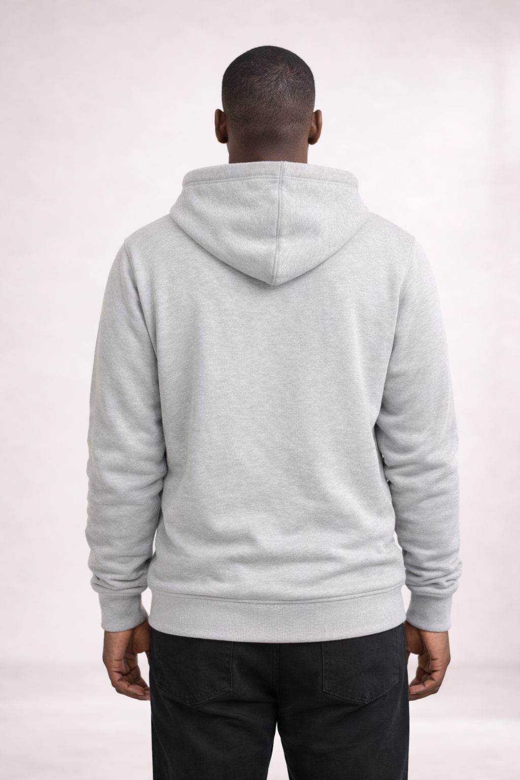 Back view of a man wearing a mens light gray pullover hoodie with hood and ribbed hem.