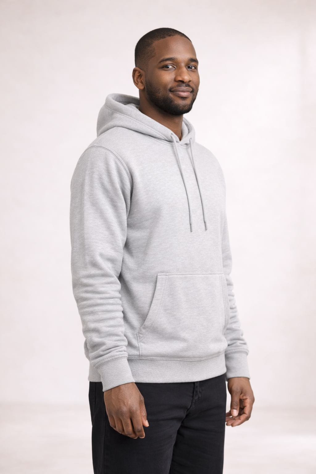 Man wearing a mens light gray pullover hoodie shown in front angled view with drawstring hood and kangaroo pocket.