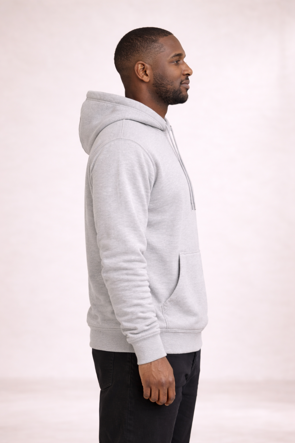 Side profile of a man wearing a mens light gray pullover hoodie showing relaxed fit and hood.