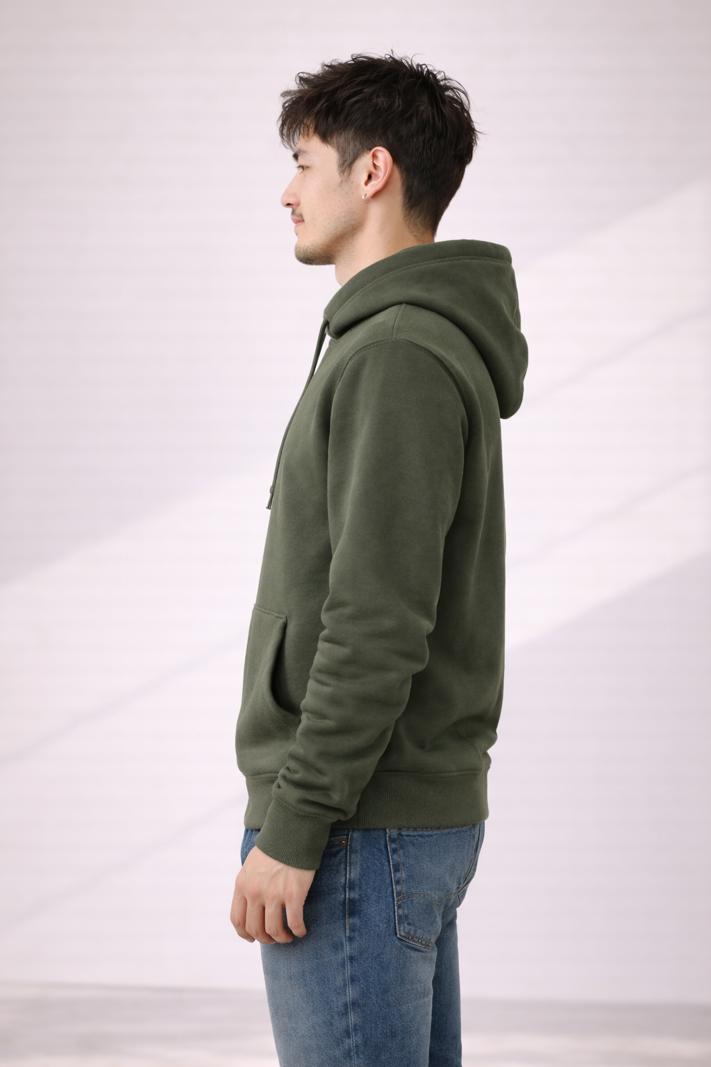 Side profile of a man wearing an olive green pullover hoodie showing relaxed fit and hood.