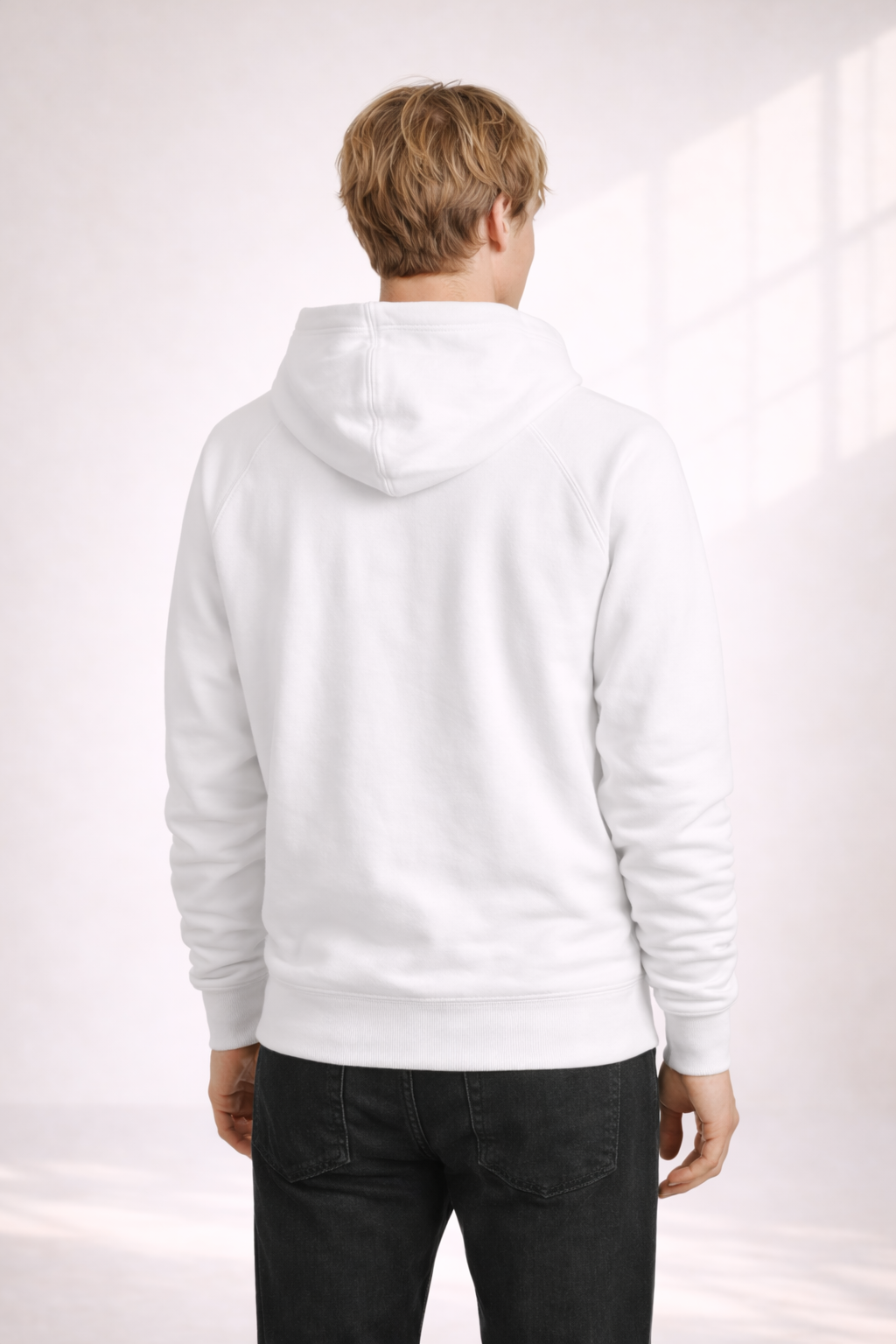 Back view of a man wearing a white pullover hoodie with hood down and ribbed hem.