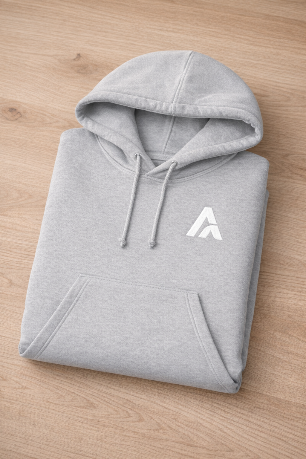 Folded gray hoodie with a white logo on a wooden surface